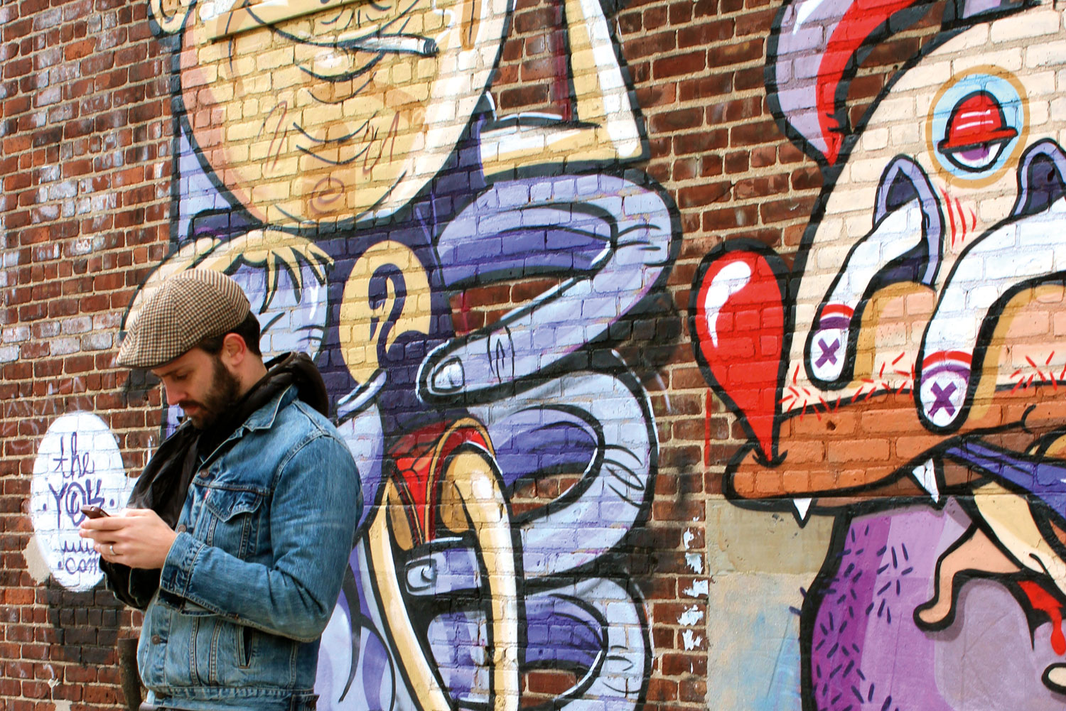 One of Brooklyn's many resident hipsters takes a break alongside some local street art.