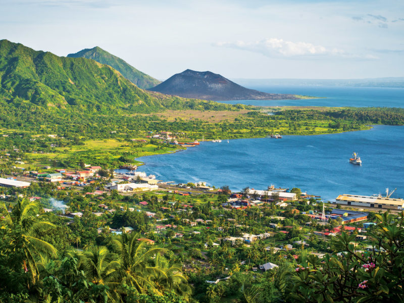 Rabaul with the dark cone of Mt Tavurvur on the horizon.