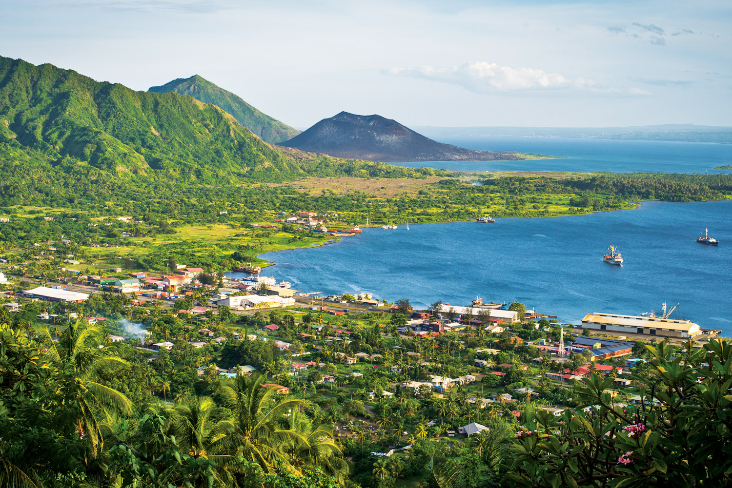 Rabaul with the dark cone of Mt Tavurvur on the horizon.