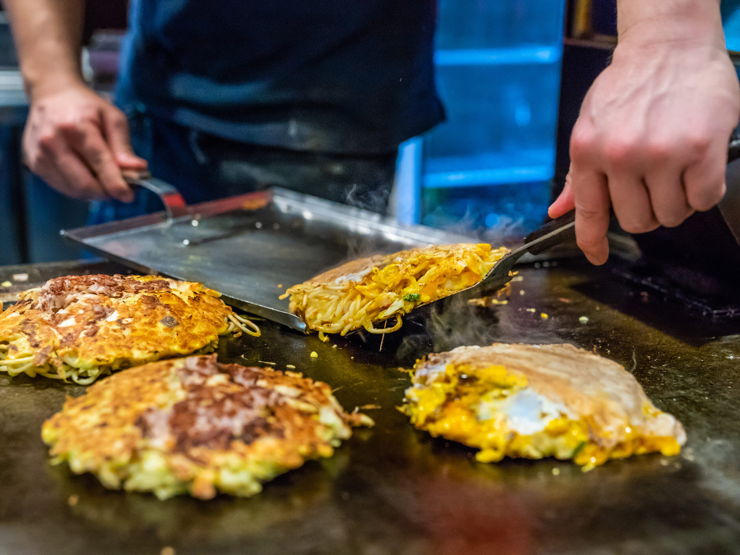 cooking Okonomiyaki on an iron plate in Osaka