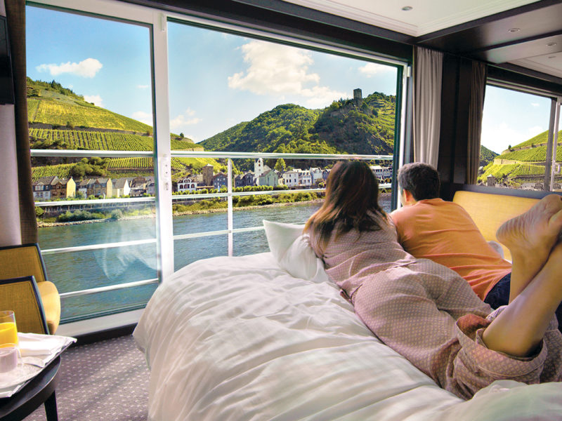 Couple looking out window of suite on river cruise in Europe