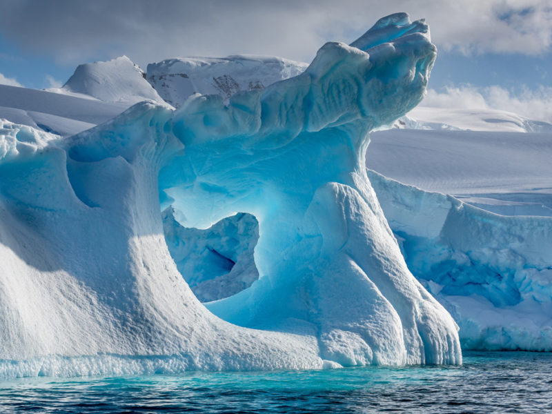 A dramatically shaped and weather eroded iceberg floating in Wilhemina Bay Antarctica