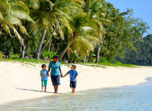 Fijian woman and kids walking on beach