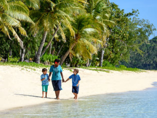 Fijian woman and kids walking on beach