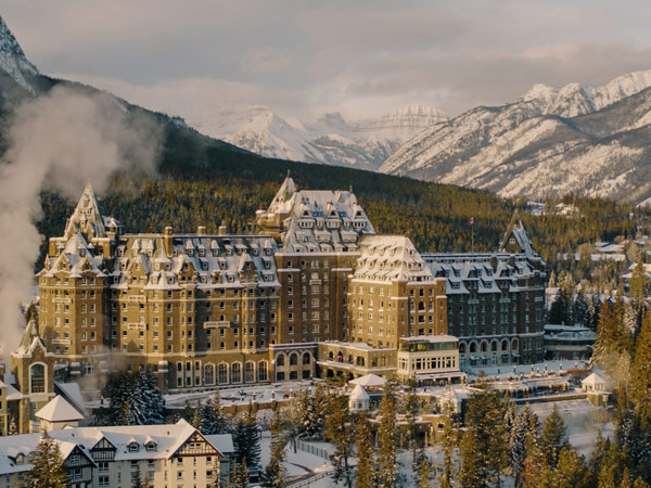 Winter shot of Fairmont Banff Springs with snow covered Christmas trees around