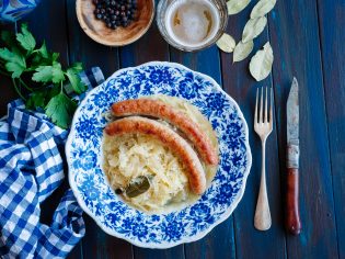 Bratwurst with sauerkraut and beer on blue table