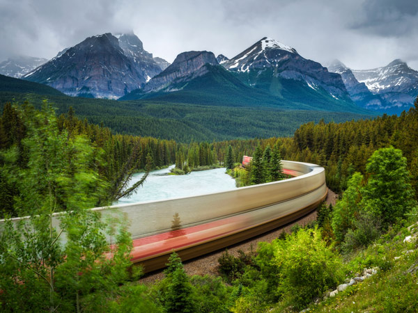Train passing through the Morant's Curve in bow valley with Rocky Mountains in the background, Banff National Park, Alberta Canada.