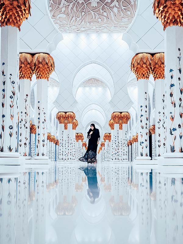 woman walks through Abu Dhabi, Sheikh Zayed Grand Mosque interior
