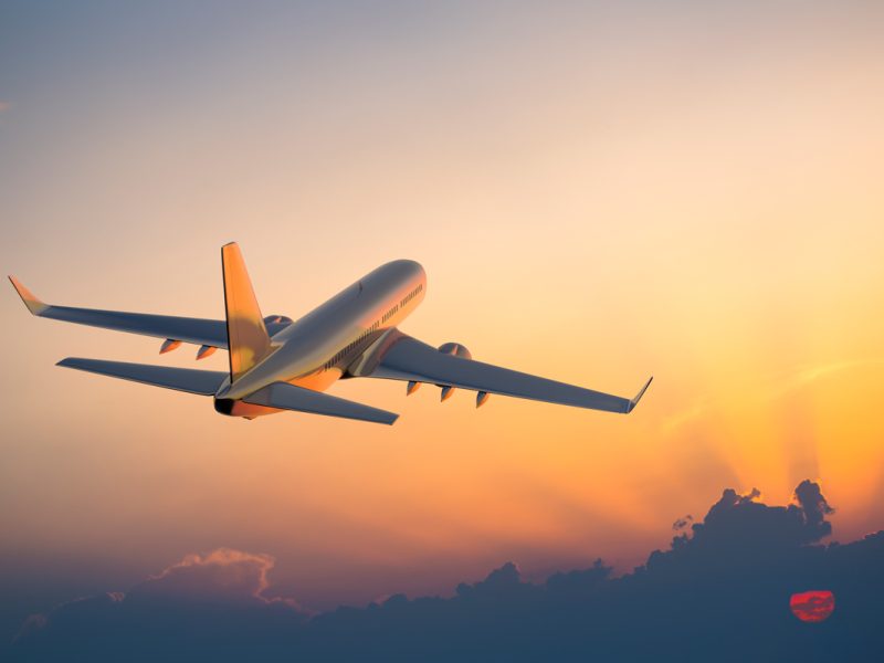 Passenger airplane flying above clouds during sunrise