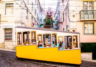 a yellow-coloured tram traversing along the Lisbon streetscape