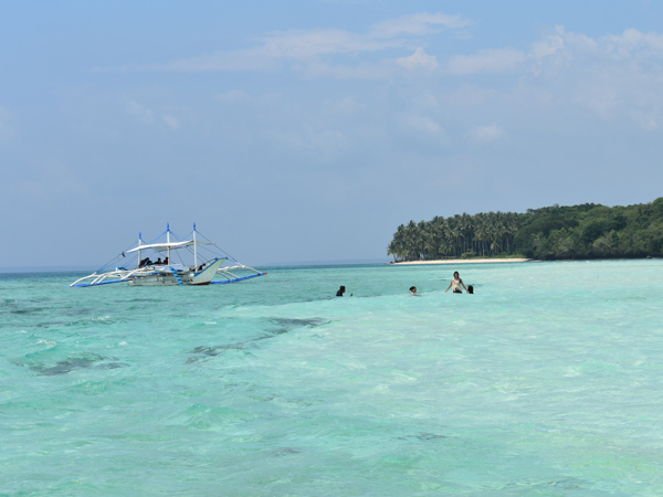 a group of tourists swimming in the clear blue waters of Mansilungan Sandbar, Balabac, Palawan