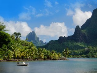 Mountains and ocean with boat in forefront on islands of Tahiti