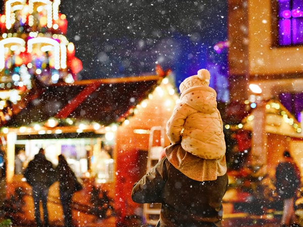 a father carrying his child on his shoulders in a Christmas market in Germany on a winter day