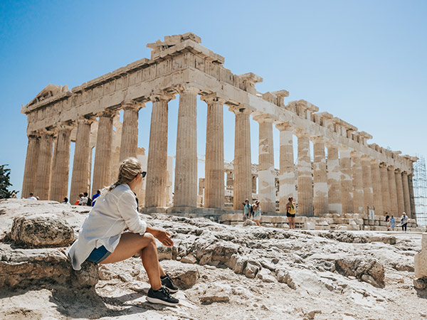 Woman relaxing while looking at Parthenon temple in greece against clear sky