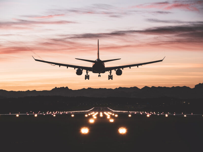 An airplane moments from touching down on the runway at sunrise.