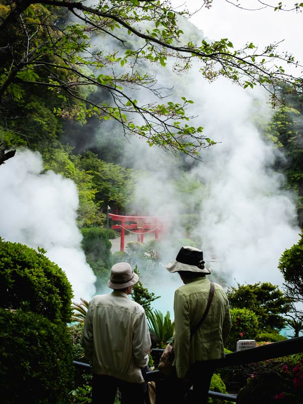 Cherry blossom tree and two men in front of Beppu hot spring and onsen in Japan