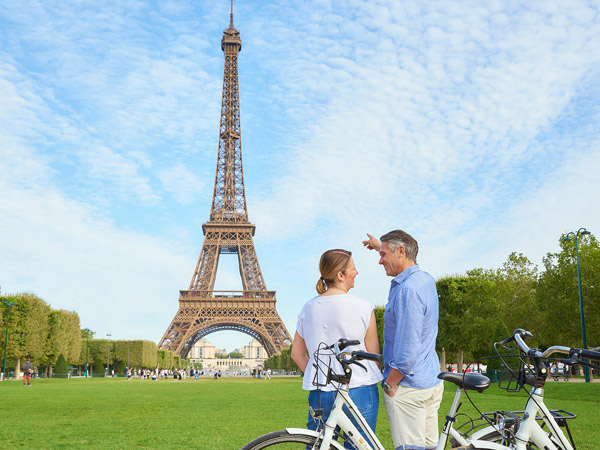 A couple admiring the Eiffel Tower in Paris during a biking excursion during the Summer.