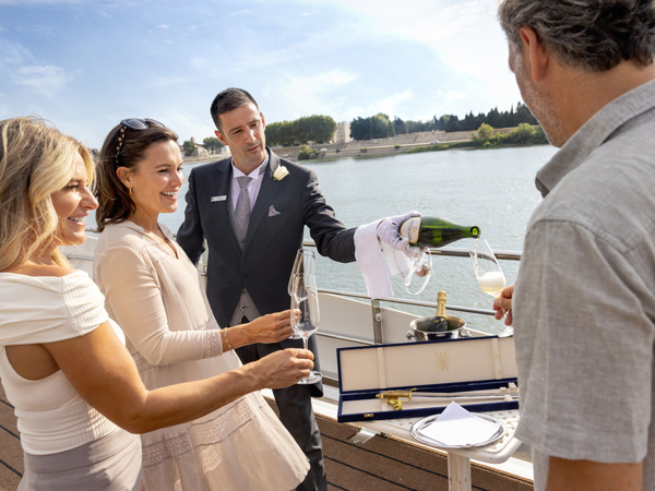 3 people being served champagne on the sundeck.