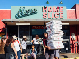 a person holding boxes of pizza outside Home Slice pizzeria, South Congress Avenue