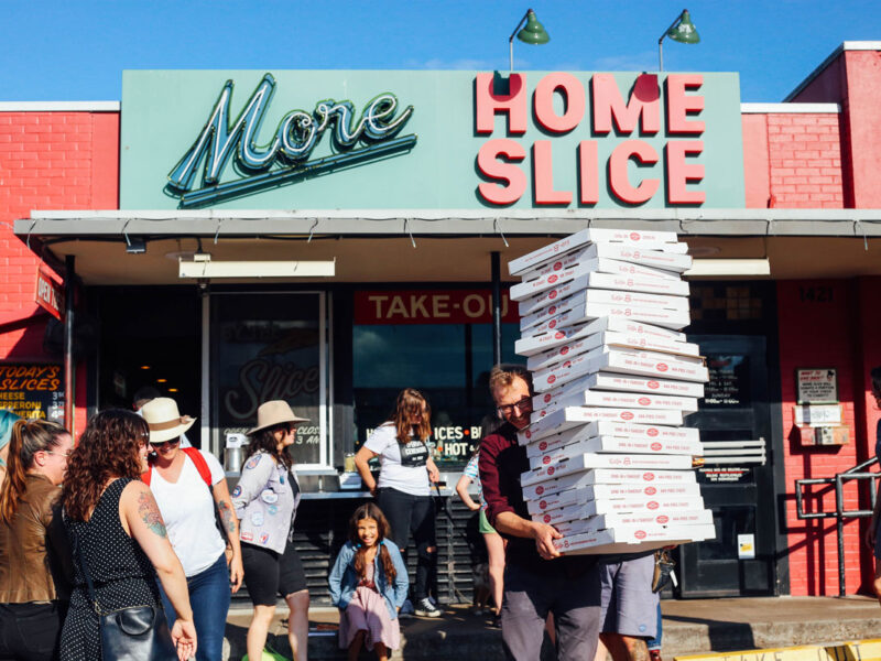 a person holding boxes of pizza outside Home Slice pizzeria, South Congress Avenue