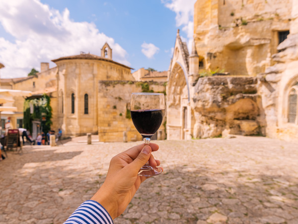 a hand holding a glass of red wine in Saint-Émilion, Bordeaux, France