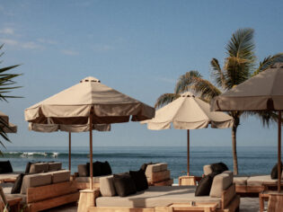 a beachfront club with umbrellas and sunbeds at The Lawn, Bali