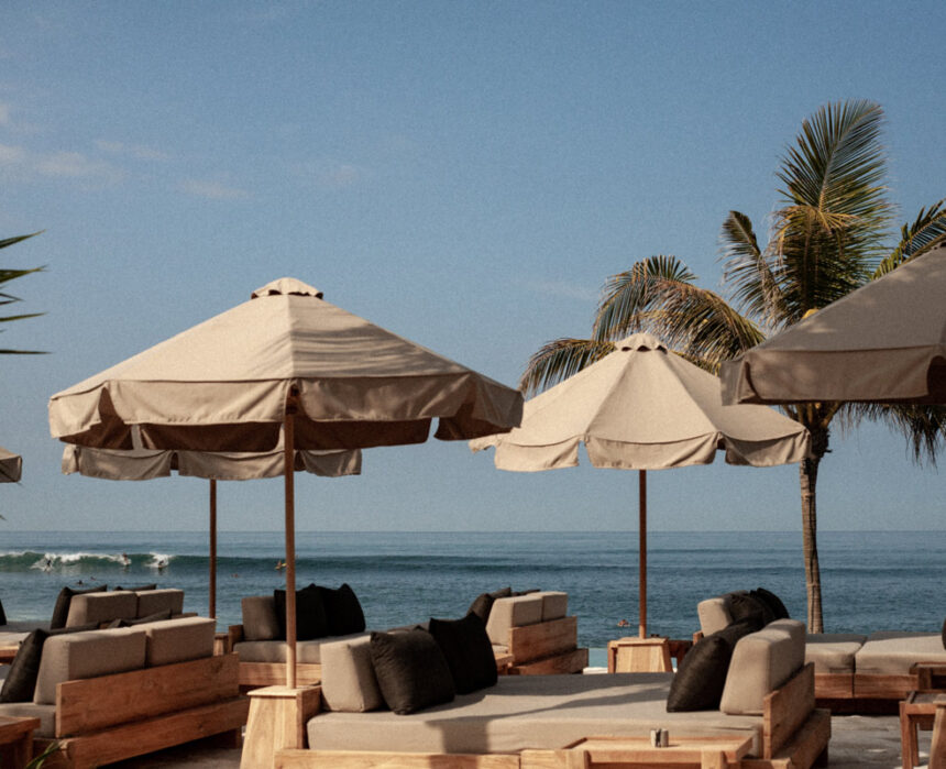 a beachfront club with umbrellas and sunbeds at The Lawn, Bali