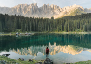 a woman standing at Lago di Carezza in Dolomites, Italy