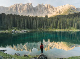 a woman standing at Lago di Carezza in Dolomites, Italy