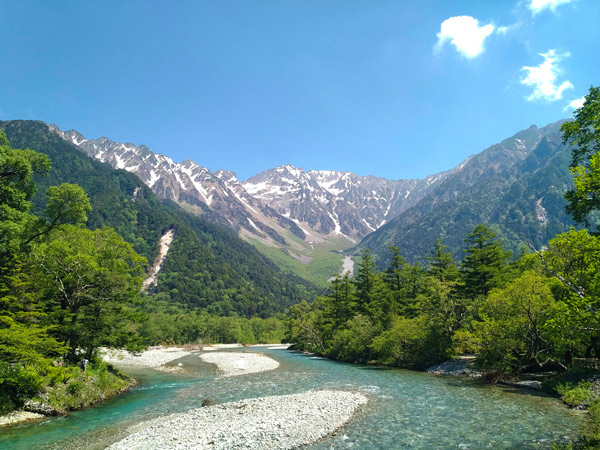 green trees near lake and mountains during daytime in Kamikochi, Japan