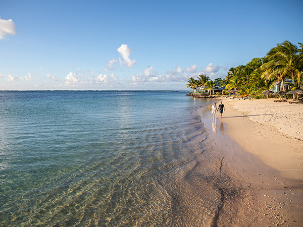 couple walking along a beach in samoa