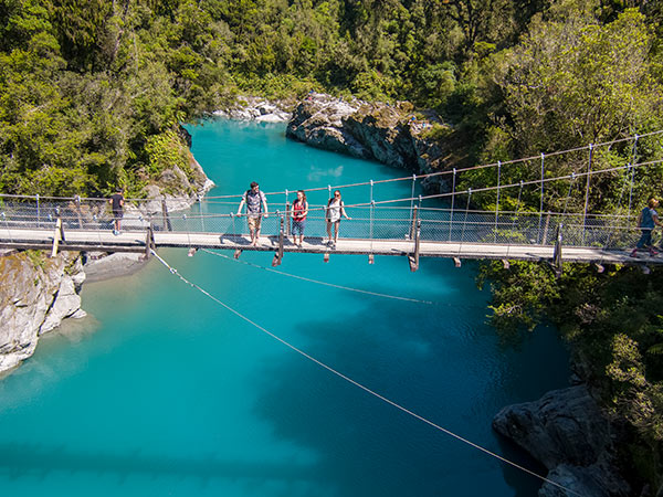 walkers crossing a bridge over Hokitika Gorge, west coast new zealand