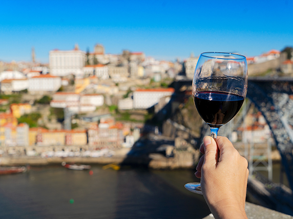 A person holding a glass of wine by the Douro River.