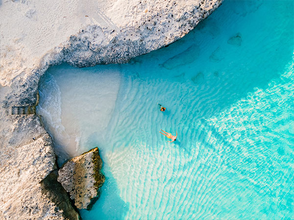 a couple of men and women on the beach of Tres Trap Aruba Caribbean Island. Tres Trapi Bay is popular with locals for snorkeling and diving in the turqouse colored ocean