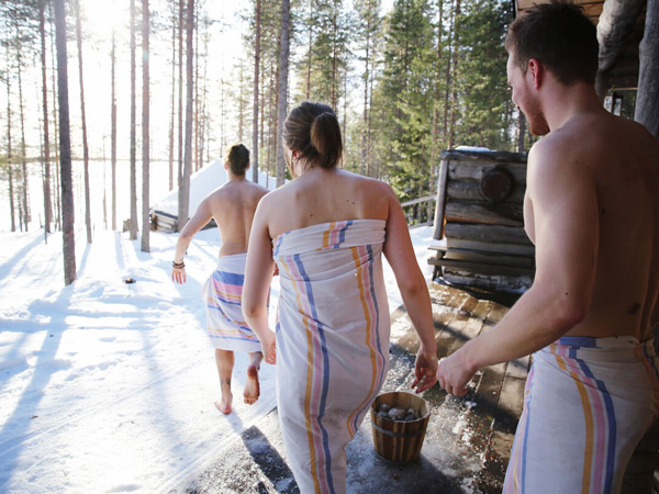 A group carrying buckets to the sauna in Ruka Kuusamo through the snow