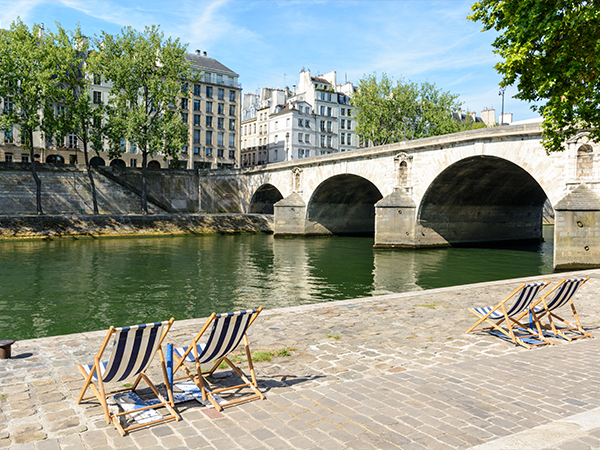 Deck chairs in the sun on the bank of the river Seine