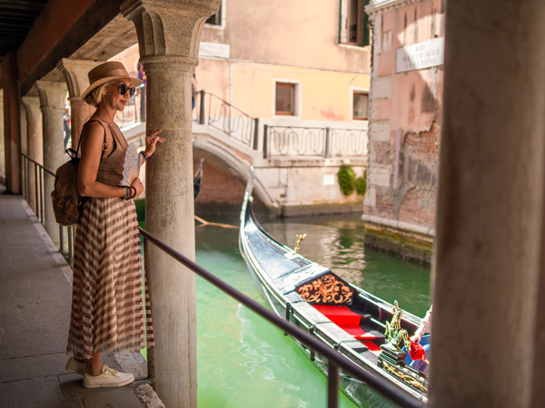 Female tourist is walking on a narrow street in Venice, Italy with handheld fan