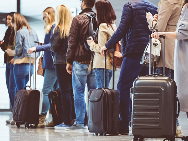 People lining up with carry-on baggage to board a flight