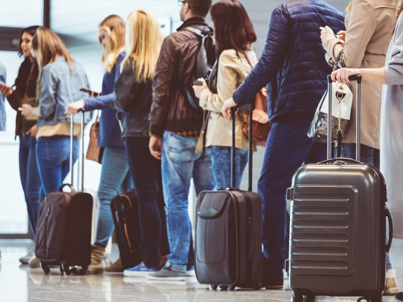 People lining up with carry-on baggage to board a flight