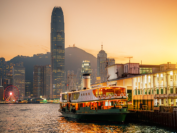 Victoria Harbor in Hong Kong paints a mesmerizing scene, the silhouette of a ferry boat adding charm to the city's twilight beauty.