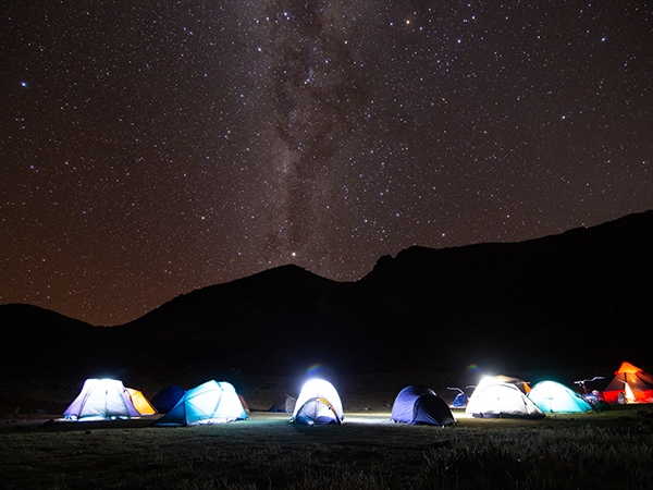 Camping tents under a star-filled sky.