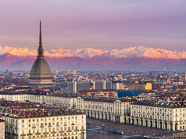 Torino (Turin, Italy): cityscape at sunrise with details of the Mole Antonelliana towering over the city. Scenic colorful light on the snowcapped Alps in the background.