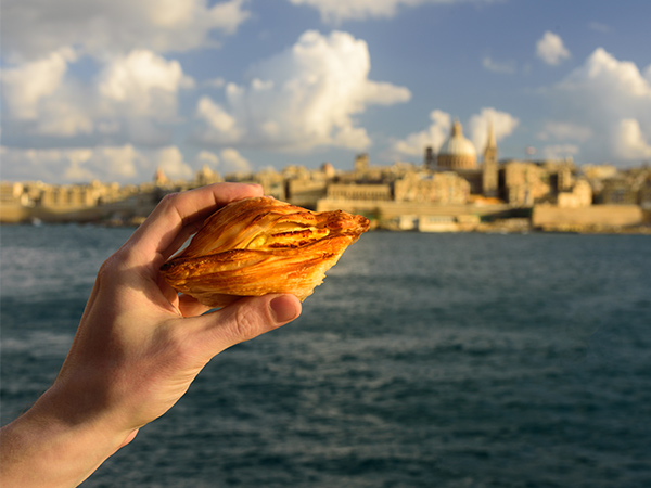 holding traditional Maltese pastry Pastizzi in Valletta