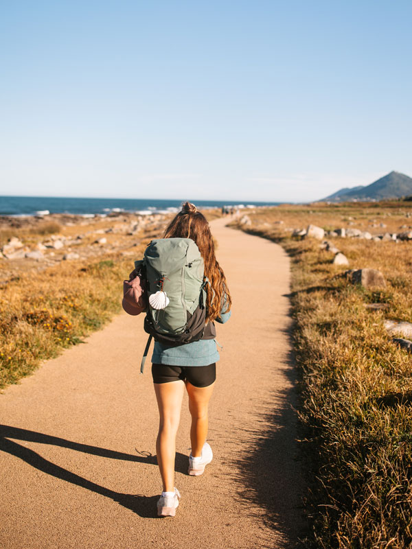a woman with a backpack walking on the Camino de Santiago