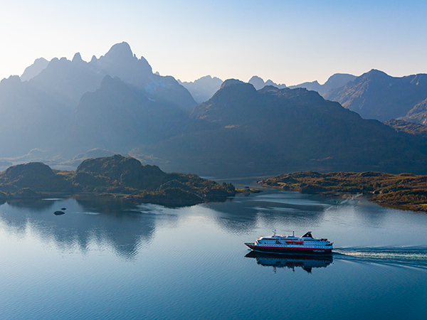 Cruising through Norway’s Lofoten Islands, a ship drifts between towering cliffs and calm seas in Northern Europe and the UK.