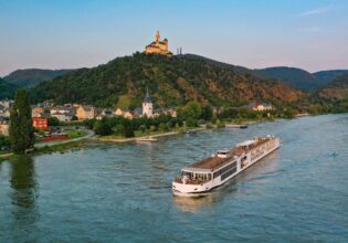 Viking River Cruise ship, the Mimir, passing the historic Marksburg Castle near Braubach on the Rhine River at sunset.