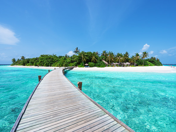 a boardwalk above turquoise blue waters in Maldives
