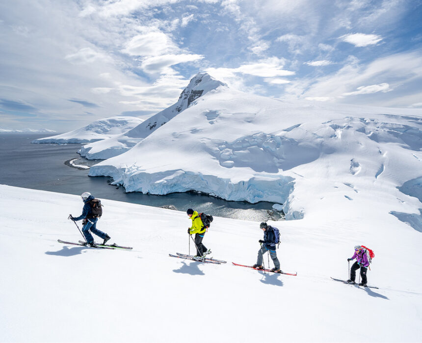 tour group skiing in antarctica with aurora