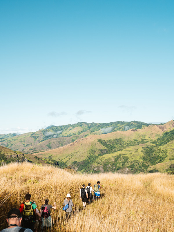 Group hikes through grasslands in Fiji's Highlands