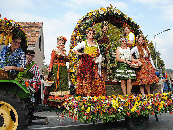 Women standing on a decorated parade float at Gamlitzer Weinlesefest.